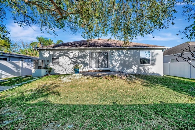 rear view of property with a lawn, fence, and stucco siding