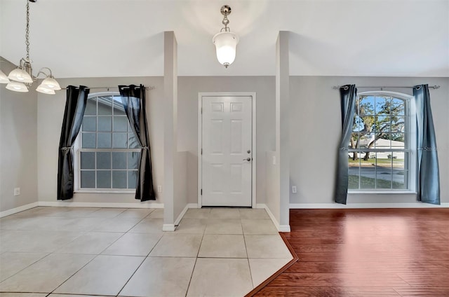 foyer with light wood-style flooring, baseboards, and a chandelier