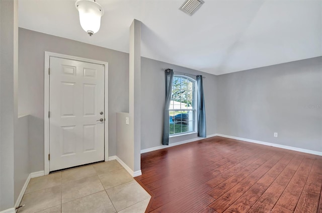 foyer entrance with light wood-style floors, baseboards, and visible vents