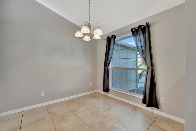 empty room with lofted ceiling, a notable chandelier, light tile patterned flooring, and baseboards