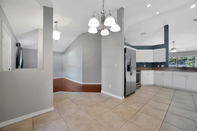 kitchen with ceiling fan with notable chandelier, white cabinetry, stainless steel appliances, light tile patterned flooring, and lofted ceiling