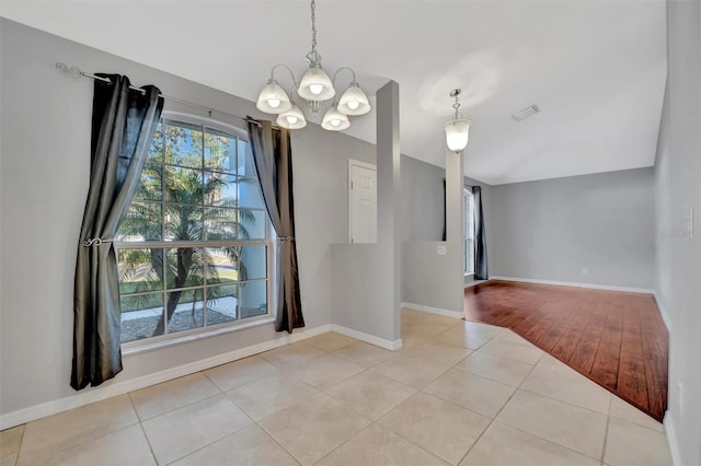 unfurnished room featuring baseboards, lofted ceiling, a chandelier, and tile patterned flooring