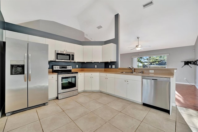 kitchen featuring visible vents, a peninsula, a sink, light countertops, and appliances with stainless steel finishes