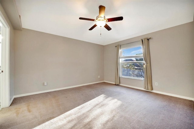 carpeted spare room with a ceiling fan and baseboards