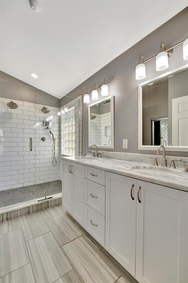 bathroom with a sink, a stall shower, and double vanity