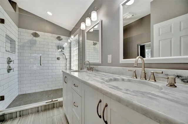 full bathroom with double vanity, a stall shower, lofted ceiling, and a sink