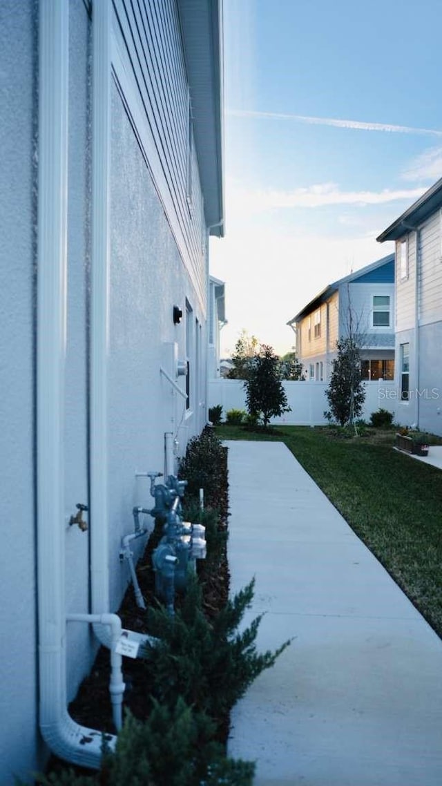 view of home's exterior with a yard, fence, and stucco siding