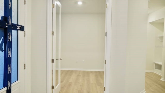 corridor featuring baseboards and light wood finished floors