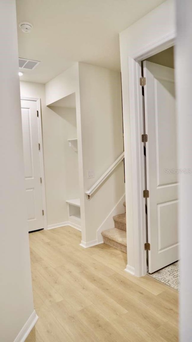 hallway with stairway, baseboards, and light wood-style floors