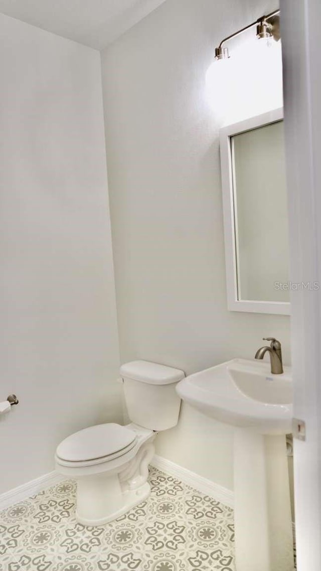 bathroom featuring tile patterned flooring, toilet, and baseboards