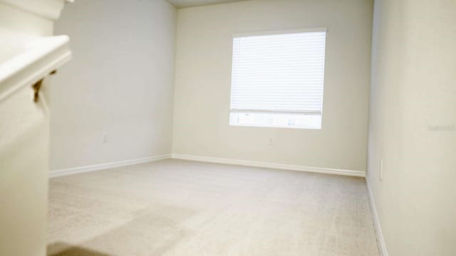 spare room with light carpet and baseboards