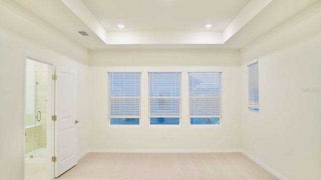 empty room with light carpet, recessed lighting, a raised ceiling, and baseboards