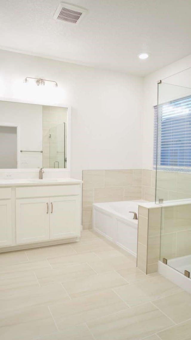 bathroom with tile patterned floors, visible vents, a shower stall, a bath, and vanity