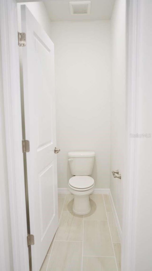 bathroom featuring tile patterned floors, visible vents, toilet, and baseboards