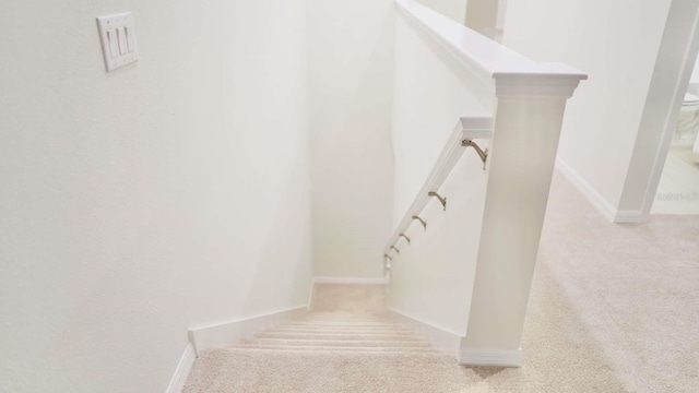 staircase featuring baseboards and carpet