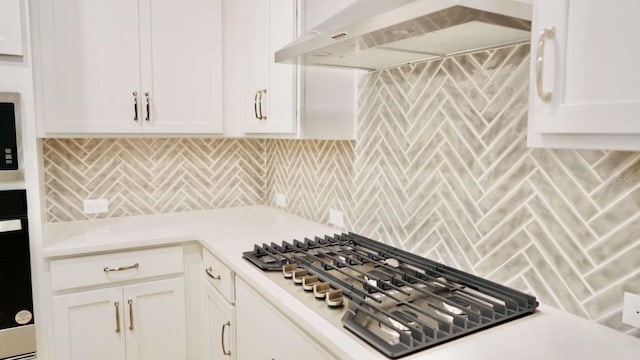 kitchen with backsplash, wall chimney range hood, stainless steel gas cooktop, light countertops, and white cabinets