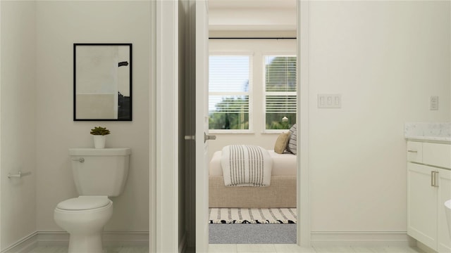 bathroom featuring connected bathroom, baseboards, toilet, and vanity