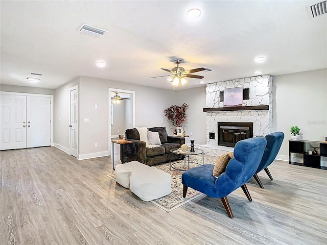 living room featuring visible vents, baseboards, light wood-style floors, and a ceiling fan