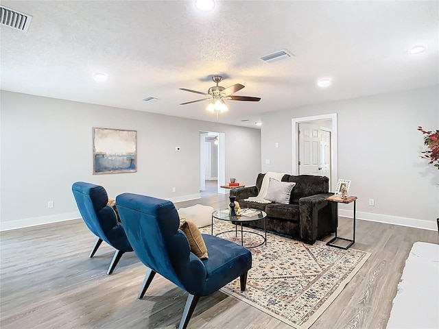 living room with visible vents, a textured ceiling, baseboards, and wood finished floors