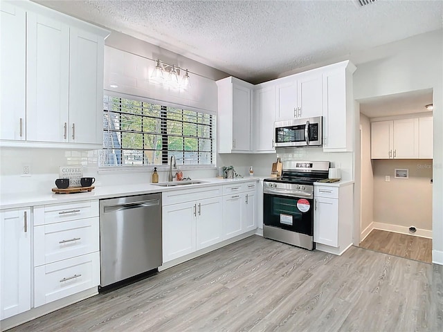 kitchen featuring light countertops, light wood finished floors, appliances with stainless steel finishes, and a sink