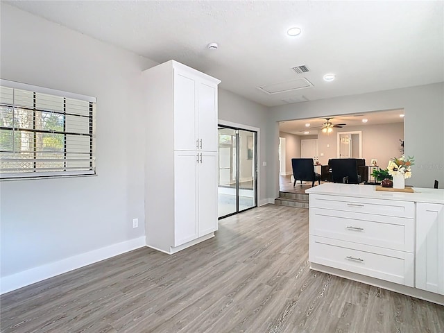 kitchen featuring visible vents, baseboards, white cabinets, and light wood finished floors