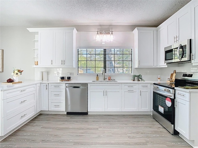 kitchen with a sink, stainless steel appliances, open shelves, and white cabinets