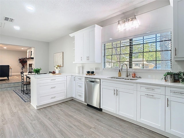 kitchen featuring a sink, dishwasher, a peninsula, and light countertops