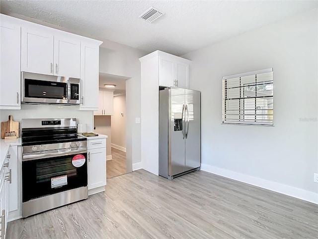 kitchen featuring visible vents, light countertops, light wood-style floors, appliances with stainless steel finishes, and white cabinetry