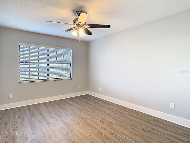 empty room with baseboards, a textured ceiling, wood finished floors, and a ceiling fan