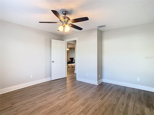 unfurnished room featuring visible vents, dark wood-type flooring, a textured ceiling, baseboards, and ceiling fan