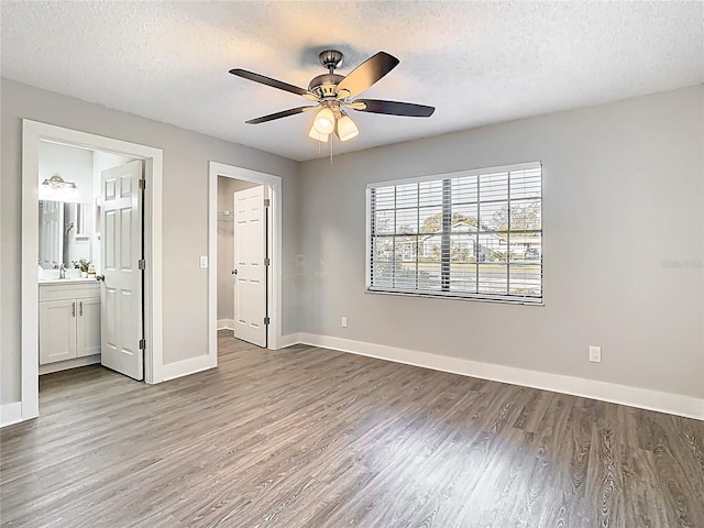 unfurnished bedroom featuring a sink, baseboards, and wood finished floors