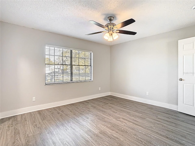 empty room featuring a textured ceiling, baseboards, a ceiling fan, and wood finished floors