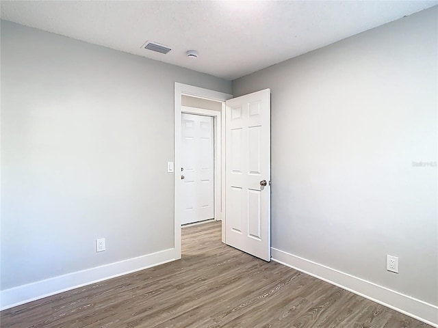 spare room featuring visible vents, baseboards, and wood finished floors