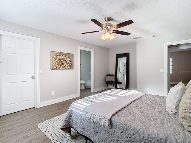 bedroom with visible vents, baseboards, wood finished floors, a textured ceiling, and a ceiling fan