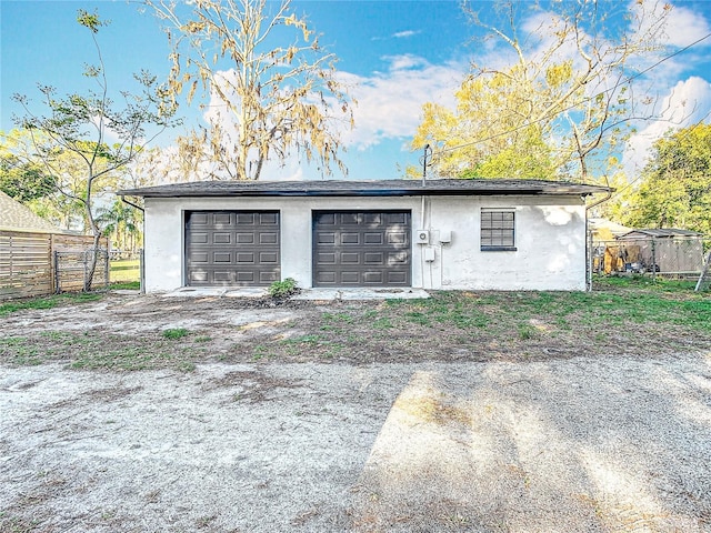 garage featuring driveway and fence