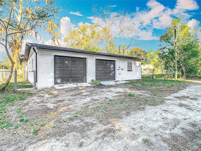 garage featuring driveway and fence