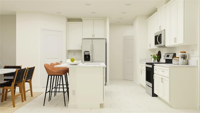 kitchen featuring a kitchen bar, a center island, appliances with stainless steel finishes, white cabinets, and baseboards