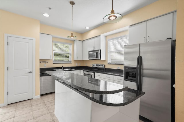 kitchen featuring a sink, appliances with stainless steel finishes, white cabinets, and pendant lighting