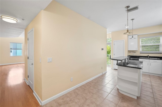 kitchen featuring dark countertops, a kitchen island, decorative light fixtures, white cabinets, and open shelves