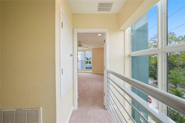 hallway featuring visible vents, a textured wall, and carpet floors