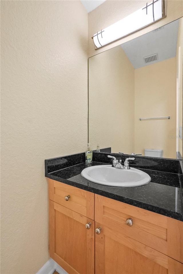 bathroom featuring visible vents, toilet, and vanity