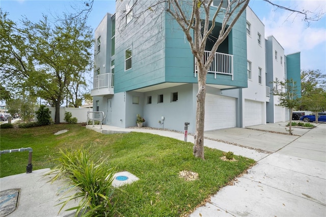 exterior space featuring stucco siding, a lawn, driveway, a balcony, and an attached garage