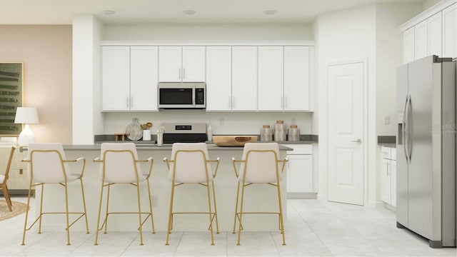 kitchen featuring white cabinetry, dark countertops, a kitchen bar, and stainless steel appliances