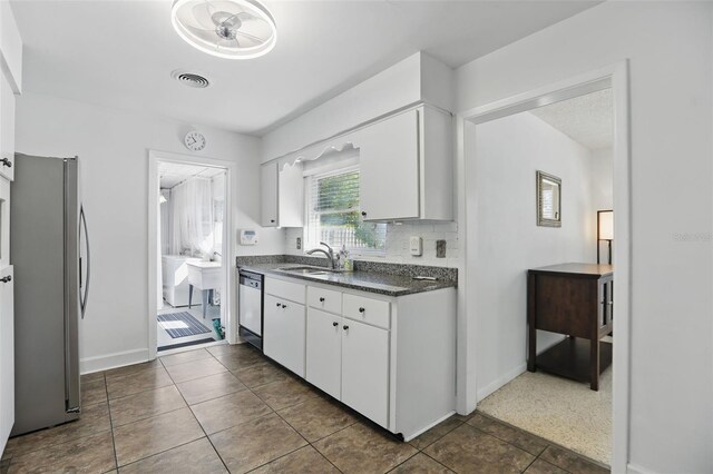 1005 Catalpa Ln, Orlando, FL 32806 - kitchen with dark countertops, white cabinets, visible vents, stainless steel appliances, and a sink