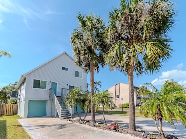 view of front of property with concrete driveway, stairway, fence, and a garage