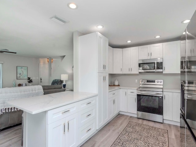 kitchen featuring white cabinetry, open floor plan, visible vents, and appliances with stainless steel finishes