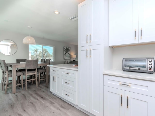 kitchen with visible vents, a toaster, light wood-style floors, white cabinets, and light countertops