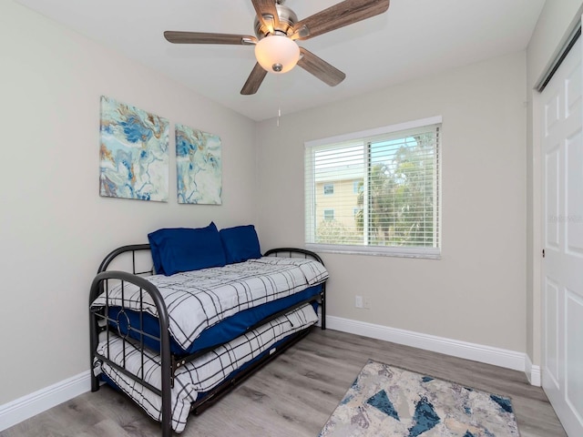 bedroom with a ceiling fan, wood finished floors, and baseboards