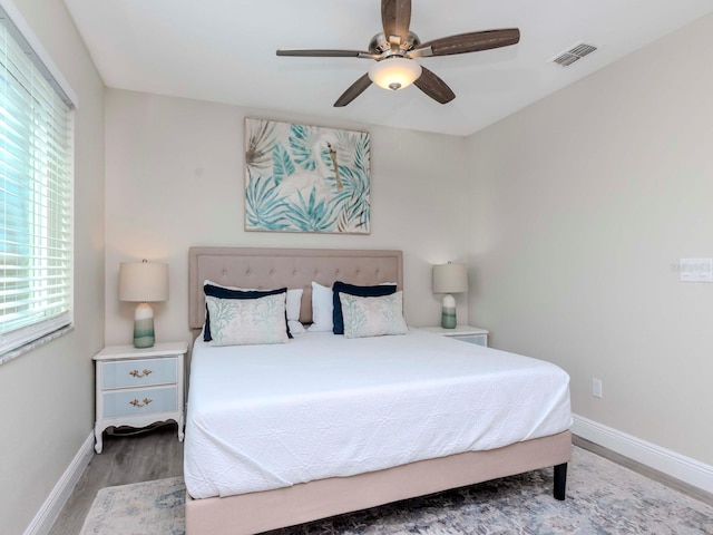 bedroom featuring visible vents, baseboards, wood finished floors, and a ceiling fan