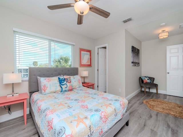 bedroom featuring visible vents, a ceiling fan, baseboards, and wood finished floors